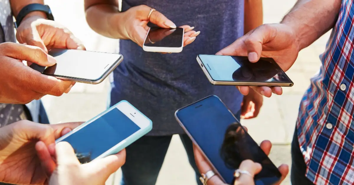 A diverse group of individuals holding their smartphones, engaged in various activities.