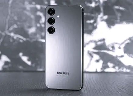 A Samsung S24 Plus smartphone with a triple camera setup, positioned vertically on a textured surface, with a blurred background.